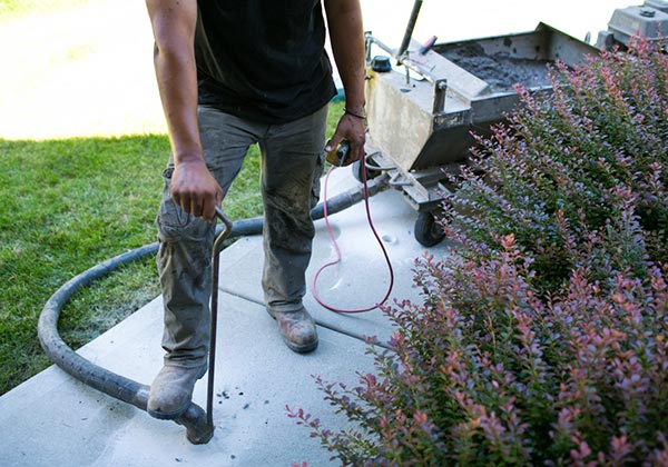 A technician leveling a sidewalk foundation with tools and equipment