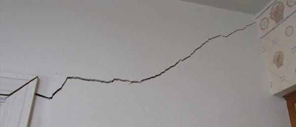 A drywall crack leading from the top of a door jam to the end of the wall