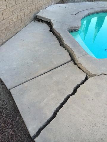 A pool deck that is cracking around the pool and in need of repair