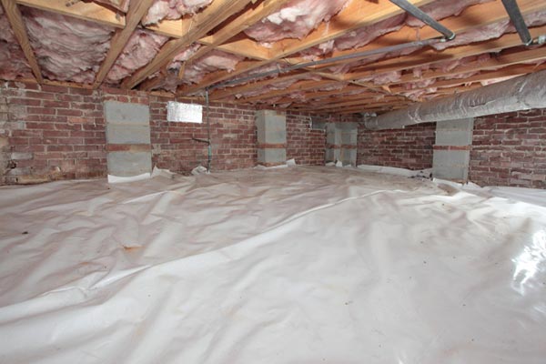 A crawl space with new insulation laid down as well as hanging insulation from the ceiling